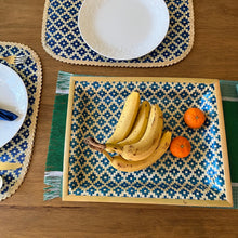 Load image into Gallery viewer, Bananas and oranges on a patterned placemat with plates and cutlery in the background.
