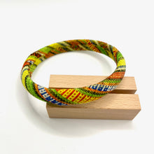 Load image into Gallery viewer, Colorful woven bracelet on a wooden block against a white background