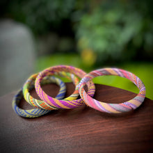 Load image into Gallery viewer, Three colorful woven bracelets on a wooden surface with a blurred natural background