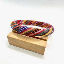 Load image into Gallery viewer, Colorful woven bracelet on a wooden stand with a white background