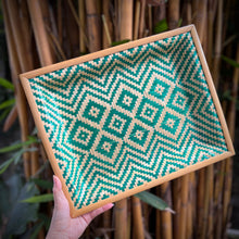 Load image into Gallery viewer, Hand holding a woven tray with green and beige pattern against a bamboo background
