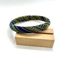 Load image into Gallery viewer, Blue and yellow patterned bracelet on a wooden block against a white background
