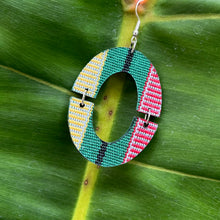 Load image into Gallery viewer, Colorful circular Filipino fabric earrings on a green leaf
